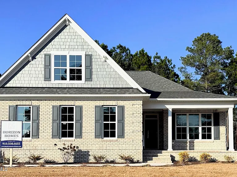 Modern gray brick house with gable roof, large windows, and a small porch. "Horizon Homes" sign nearby, representing a home builder.