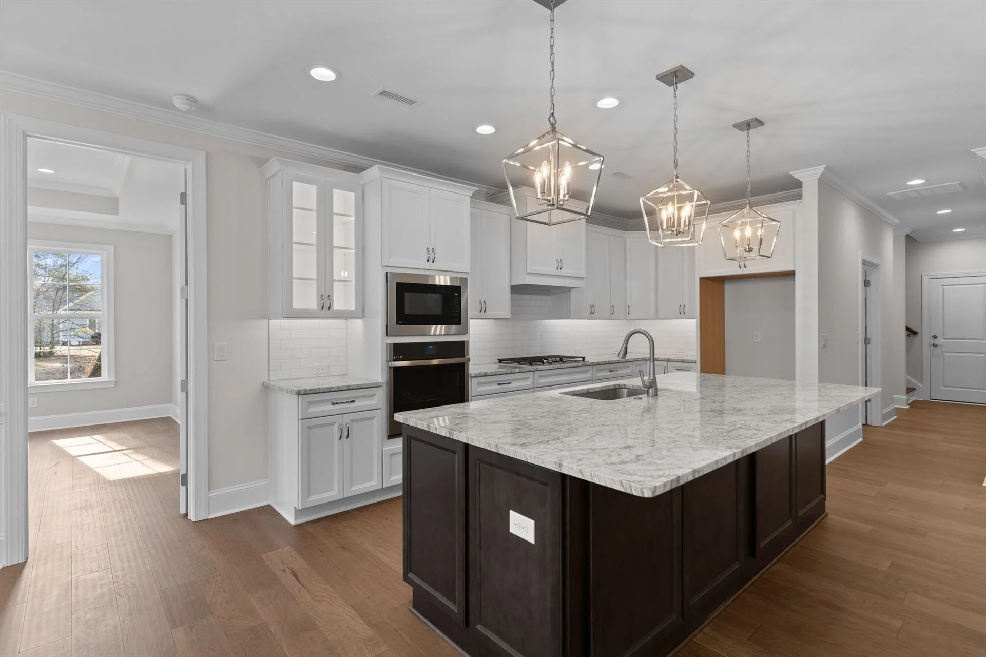 Modern kitchen with marble island, pendant lights, and stainless appliances. Ideal for home builders showcasing elegant and functional design.
