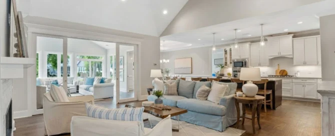 Spacious open-concept living area with light decor, cozy seating, and modern kitchen; a home builder's elegant design.