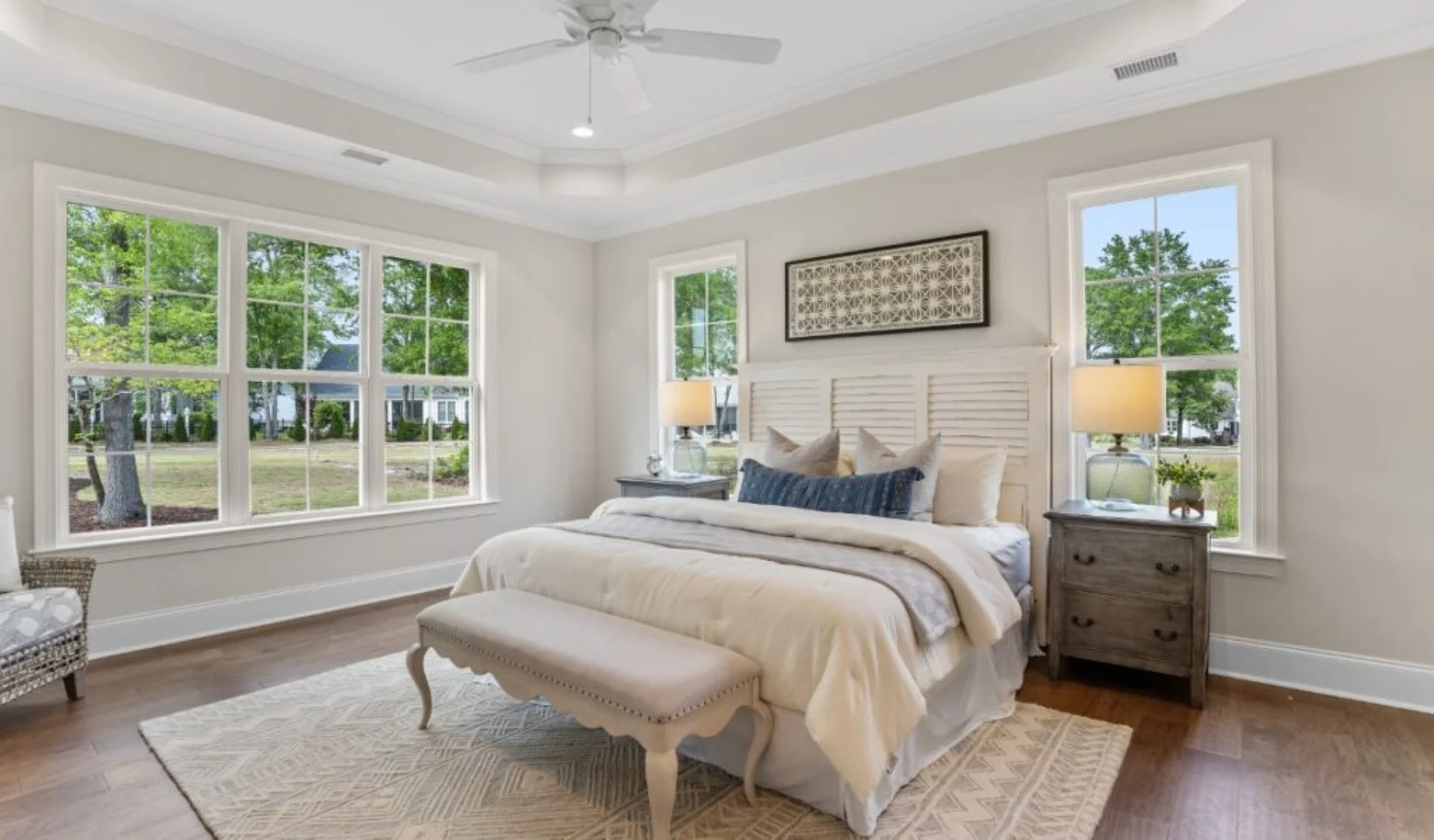 Spacious bedroom with large windows, elegant decor, and natural light, showcasing a home builder's attention to detail and craftsmanship.