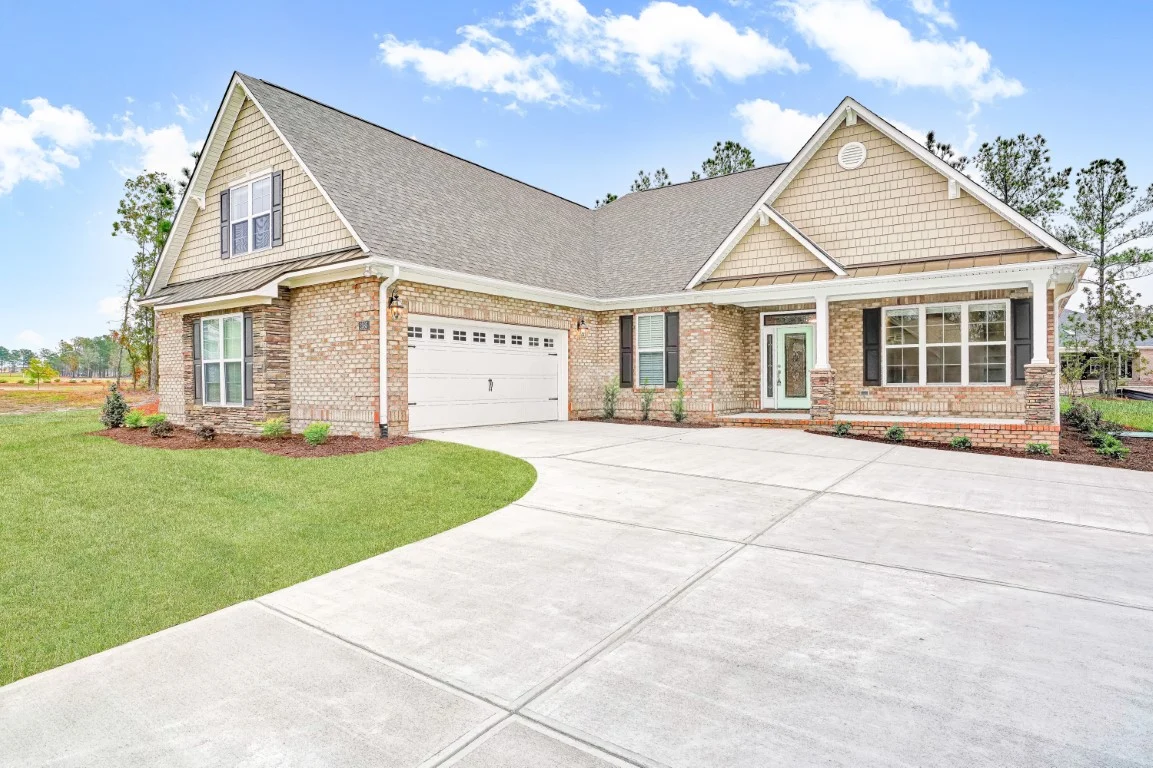 gallery-exteriors (13) Modern brick home with large garage, gabled roof, and manicured lawn; ideal for home builder showcasing craftsmanship.
