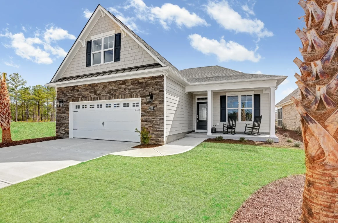 gallery-exteriors (15) Modern suburban house with stone facade, white garage, and cozy porch. Ideal design by home builder amidst lush greenery under a clear sky.