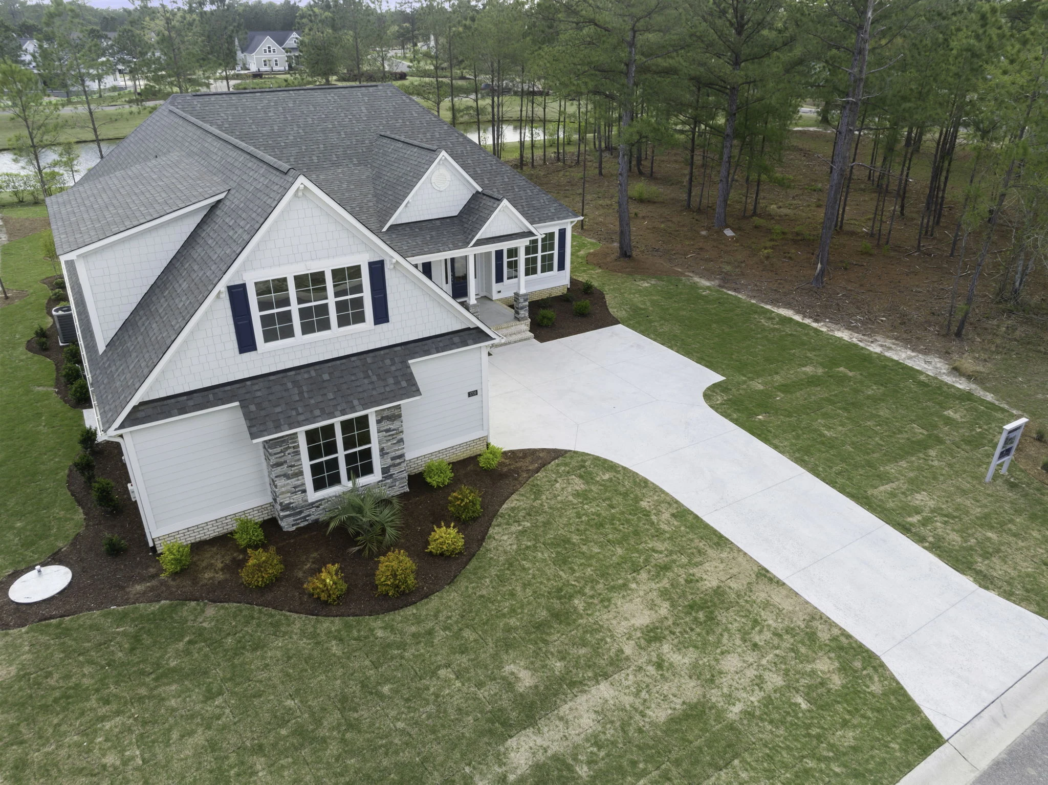 gallery-exteriors (25) Modern suburban home with gray roof, landscaped yard, and wooded surroundings, showcasing the expertise of a home builder.