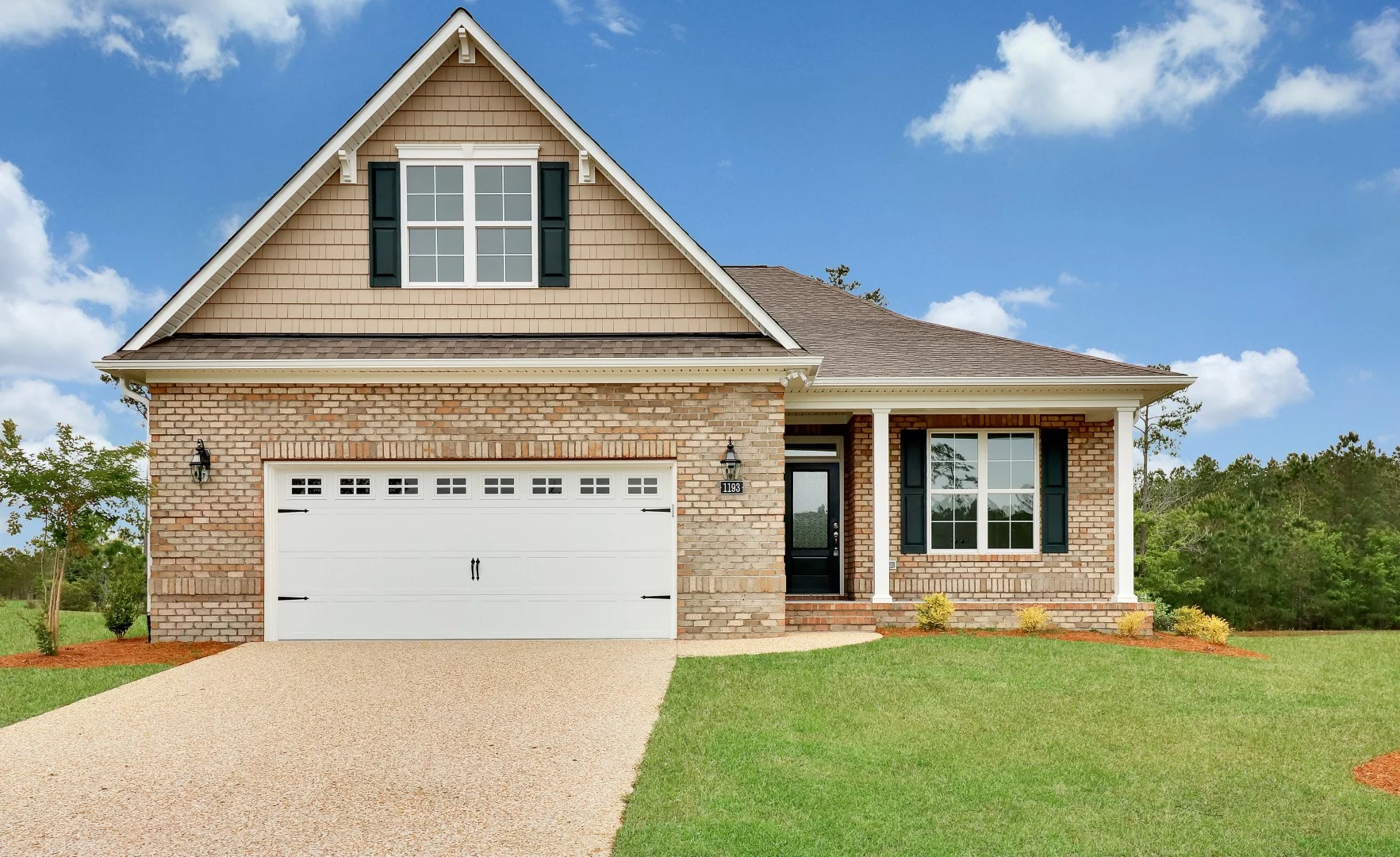 gallery-exteriors (26) Charming single-story brick house with gabled roof, large garage, manicured lawn. Ideal design for home builder projects.