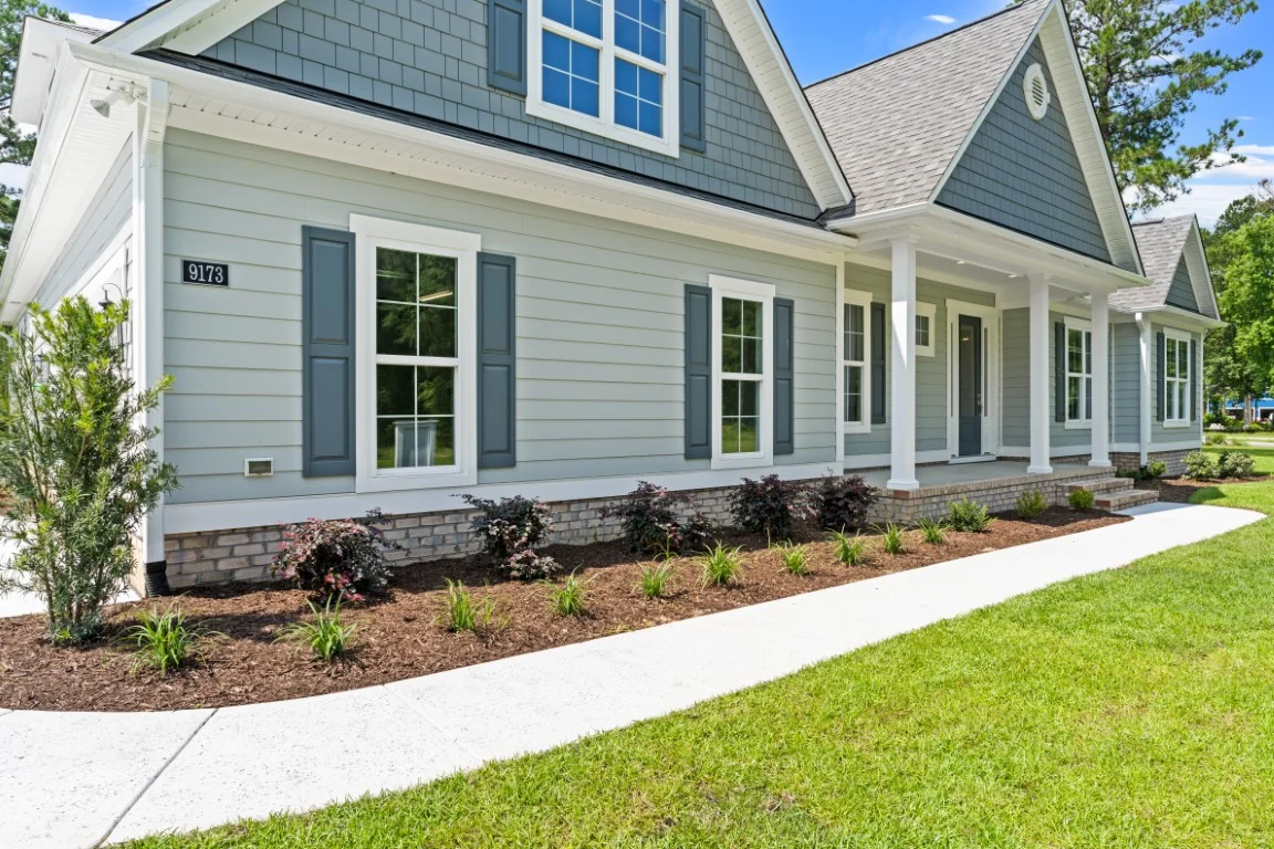 gallery-exteriors (33) Modern suburban home with gray siding, covered porch, and landscaped yard, showcasing a home builder's craftsmanship.