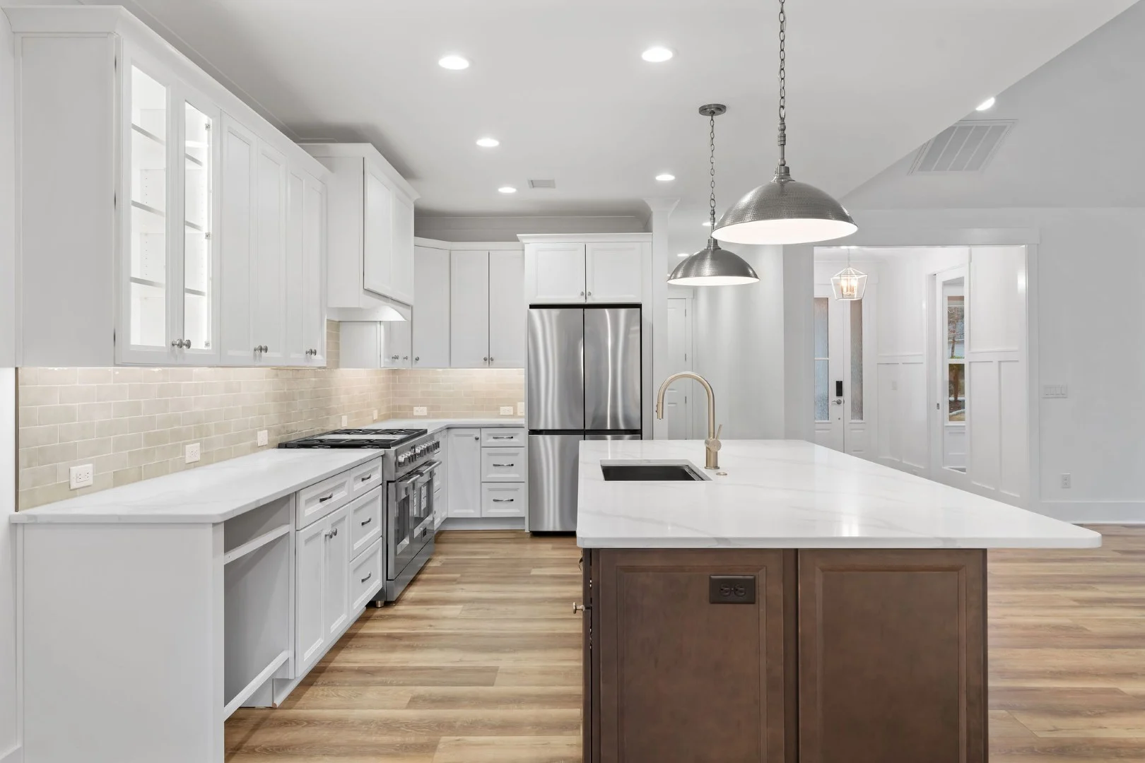 gallery-kitchen (13) Modern kitchen with white cabinetry, stainless steel appliances, and island lighting. Designed by a home builder for functionality and style.