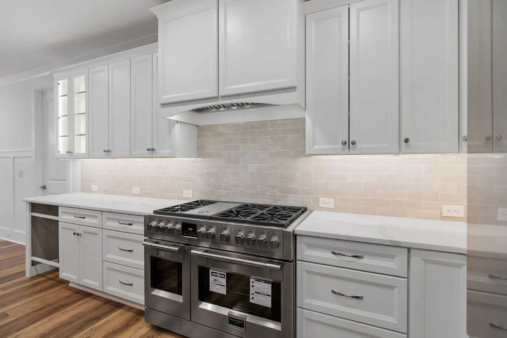 gallery-kitchen (14) Modern kitchen with white cabinets, stainless steel stove, and subway tile backsplash. Ideal design by a home builder.