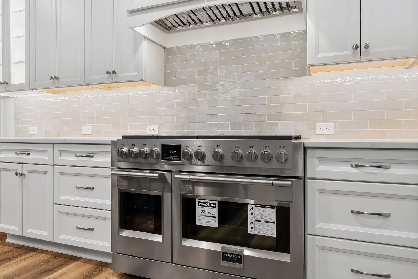 gallery-kitchen (16) Modern kitchen with stainless steel dual oven, white cabinets, subway tile backsplash, and hardwood floor, designed by a home builder.