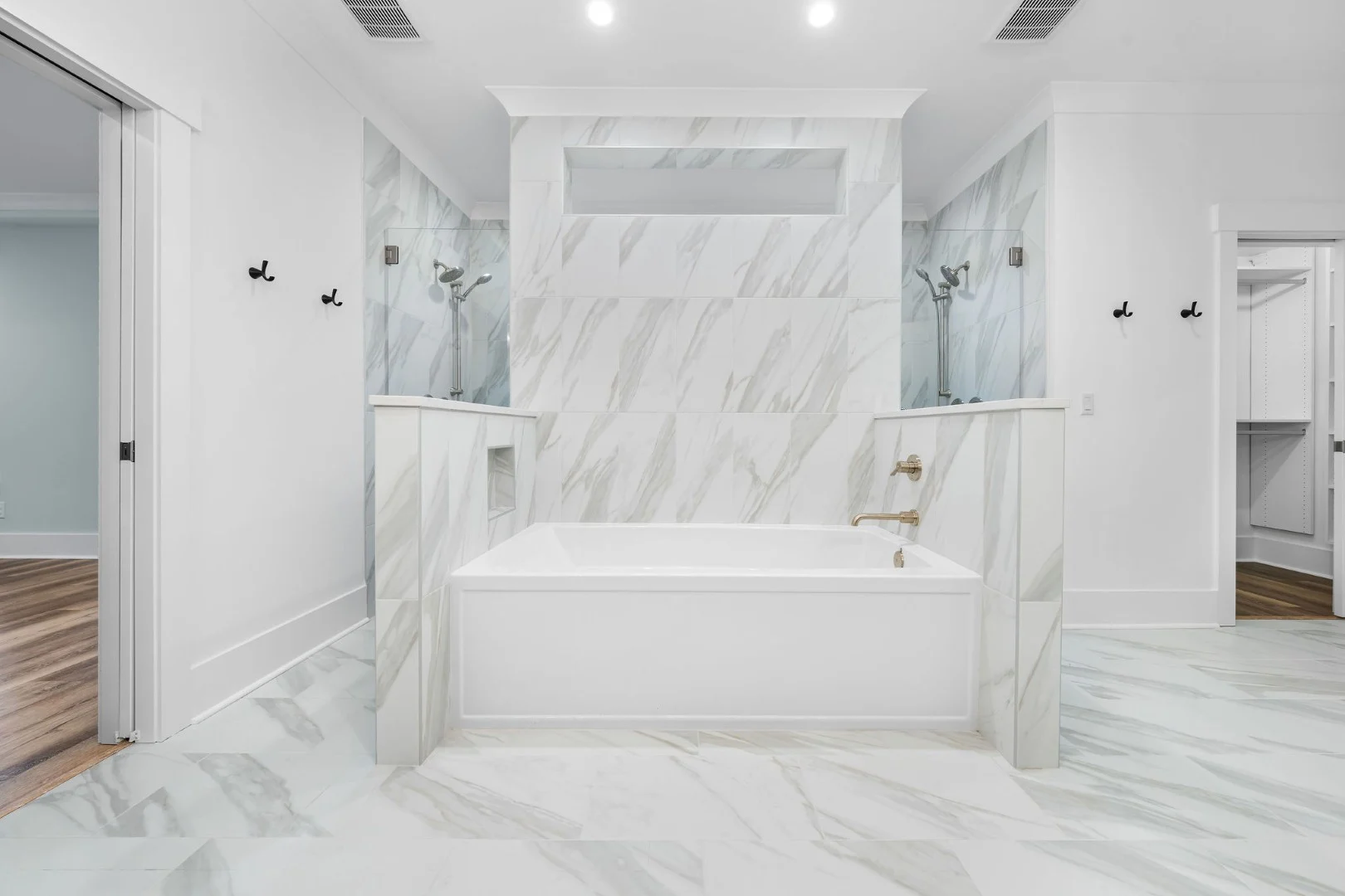 gallery-kitchen (22) Luxurious bathroom featuring a marble tile design with a recessed bathtub and modern fixtures, ideal for a home builder's portfolio.