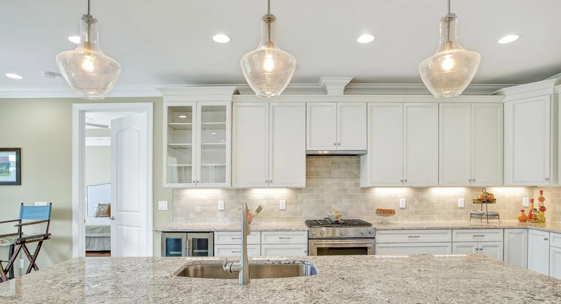 gallery-kitchen (46) Modern kitchen with pendant lights, marble countertops, and stainless steel appliances, showcasing the work of a skilled home builder.