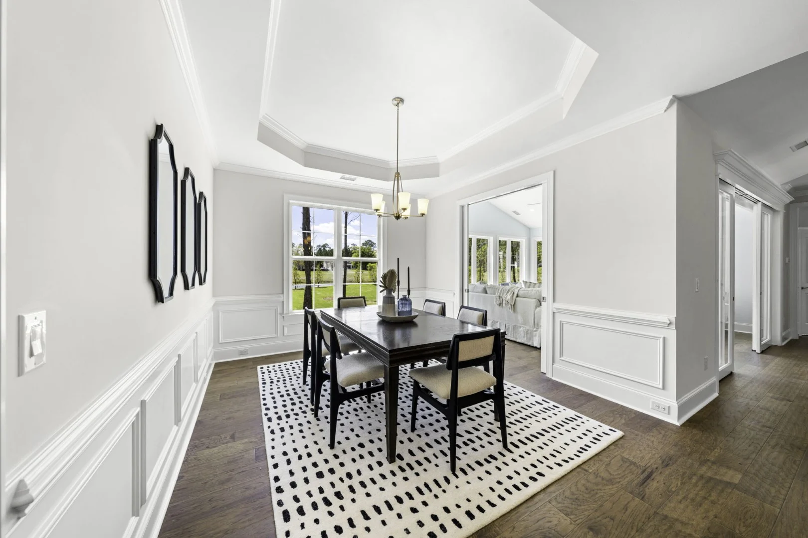gallery-kitchen (5) Elegant dining room with a dark table, six chairs, patterned rug, and view into a bright living space, showcasing modern home builder design.