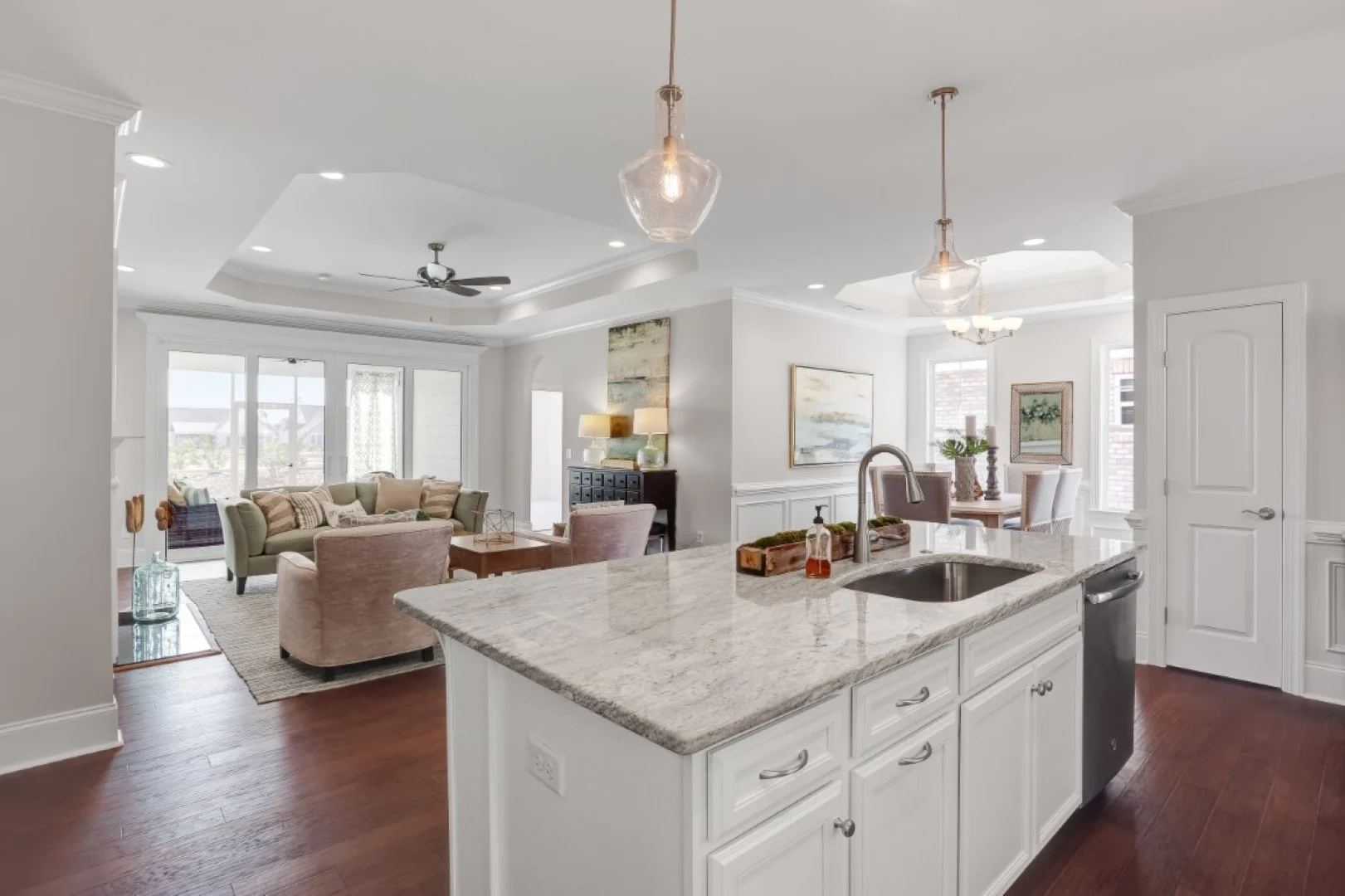 gallery-kitchen (53) Modern open-plan living area with kitchen island, granite countertops, pendant lighting, and cozy seating; ideal for a home builder showcase.