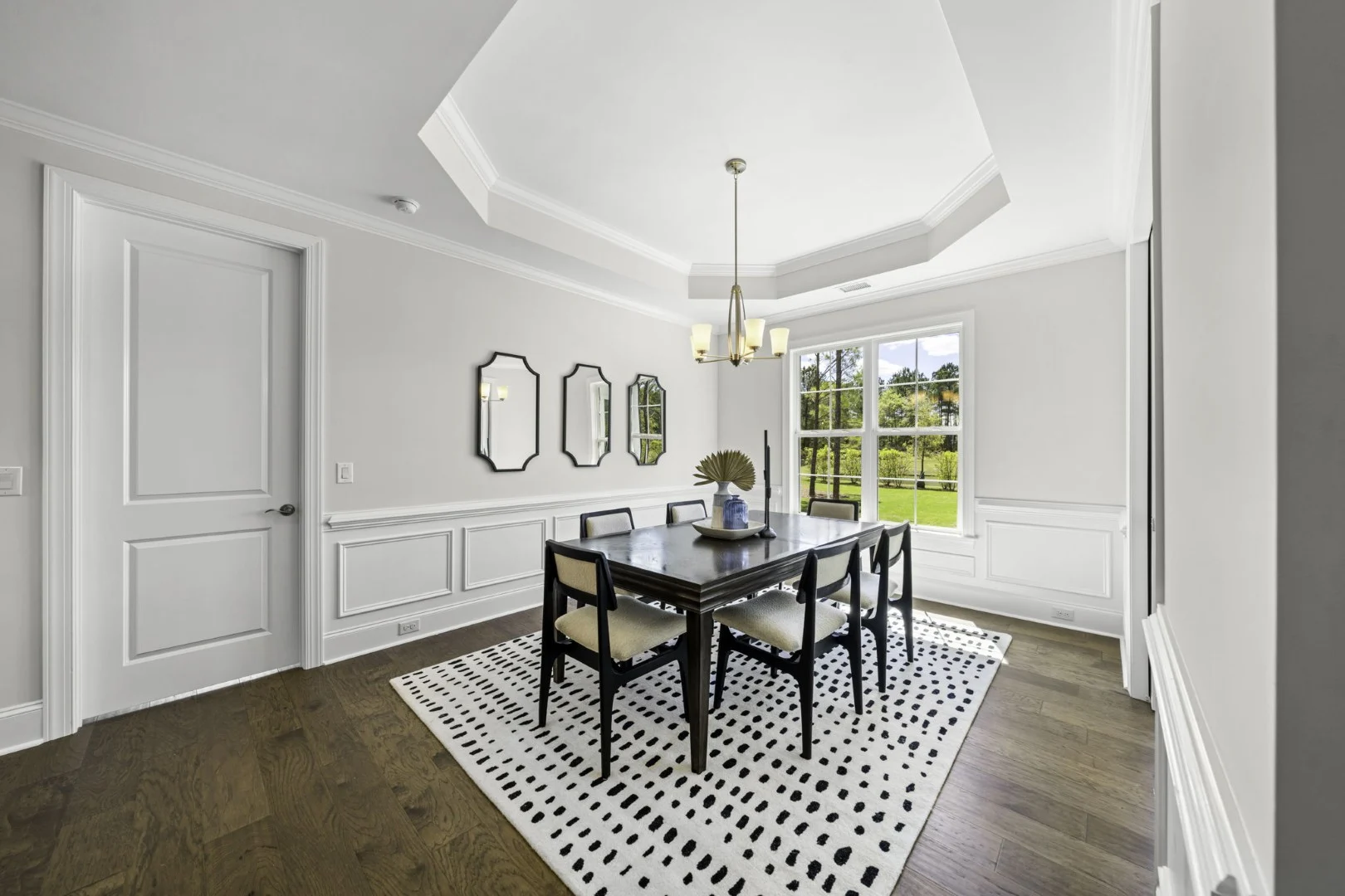gallery-kitchen (6) Elegant dining room with white walls, dark wood table, geometric mirrors, and large window, showcasing impeccable home builder design.