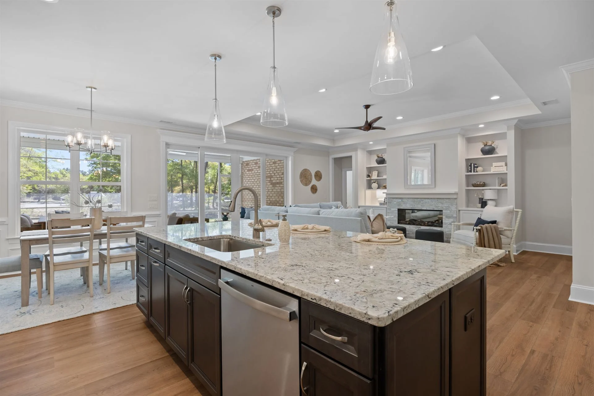 Modern open-concept kitchen and living area with granite island, large windows, and cozy seating. Ideal design by a skilled home builder.