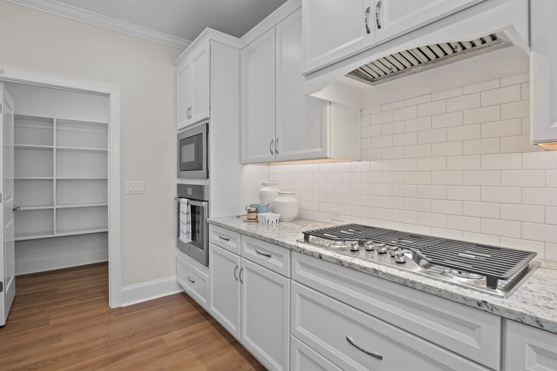 Modern kitchen with white cabinetry, stainless steel appliances, granite countertops, and subway tile backsplash by home builder.