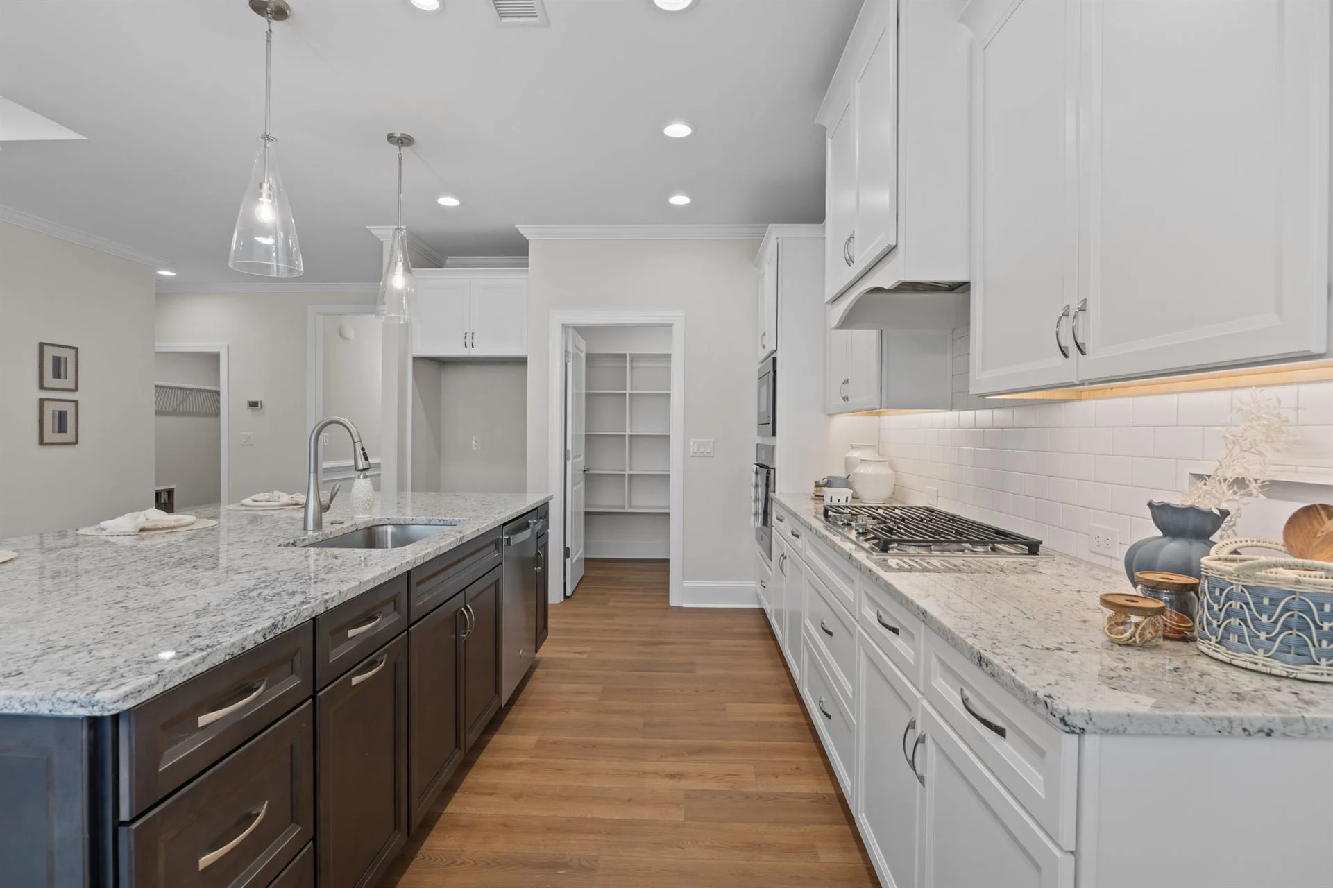 Modern kitchen with granite countertops, white cabinets, dark island, and stainless steel appliances, showcasing home builder craftsmanship.
